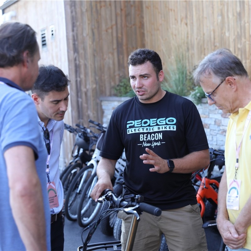An image of Pedego Beacon's store owner, Kyle Perrucci, selling a bike to three people gathered around an e-bike.